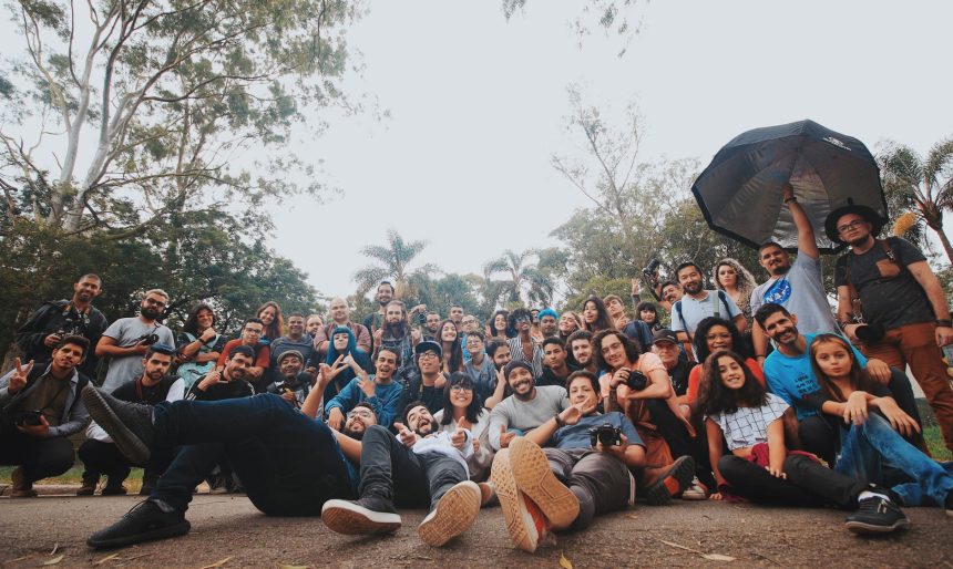 Grupo diverso de pessoas reunido ao ar livre, próximo a plantas, olhando para a câmera