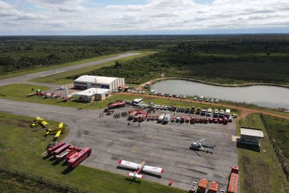 Vista aérea de uma base de combate a incêndios com caminhões, helicópteros e aviões preparados para a ação.