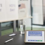 Tablet exibindo uma tela de votação em uma seção eleitoral interna, com sinalização relacionada ao dia da eleição