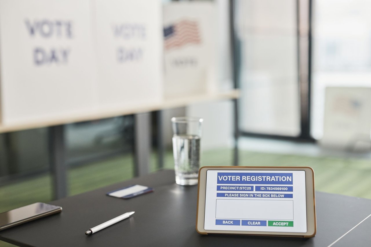 Tablet exibindo uma tela de votação em uma seção eleitoral interna, com sinalização relacionada ao dia da eleição